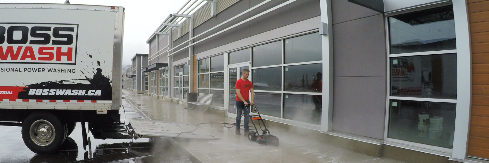 employee pressure cleaning the sidewalk in front of a store